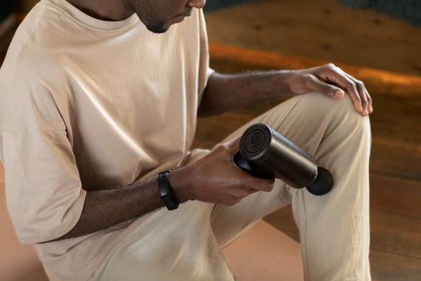 jongen die massagegun gebruikt