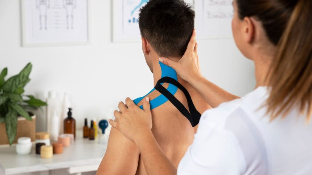 Behandelaar brengt kinesiotape aan op schouder en nek van patiënt voor herstelproces