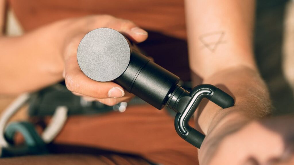Persoon gebruikt een massagegun op de onderarm voor effectief spierherstel na inspanning