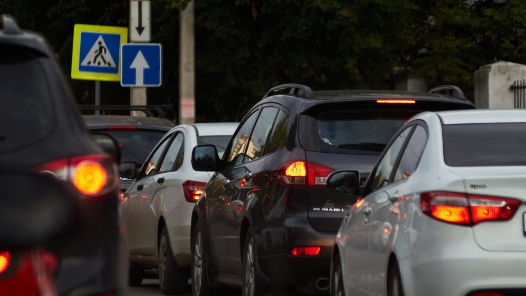 Druk verkeer bij kruispunt met stilstaande auto’s en remlichten tijdens spitsmoment